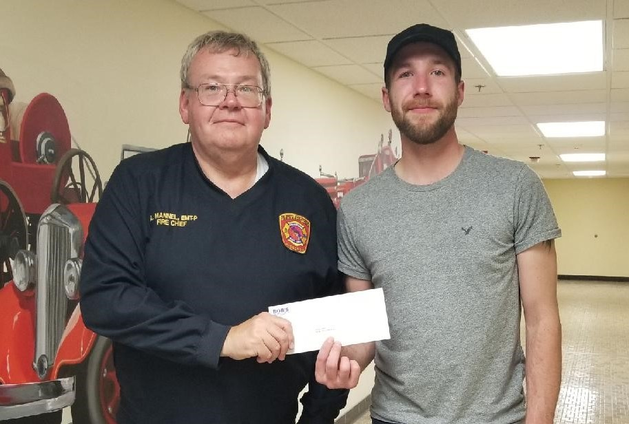 Beaver Dam Fire Chief Alan Mannel (left) presents Zachary Sletto (right) with a gift certificate from Bob’s Discount Furniture.