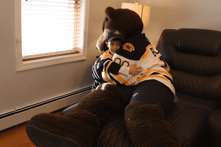 Grant Medeiros hugs Blades, the Boston Bruins mascot | Bob's Discount Furniture