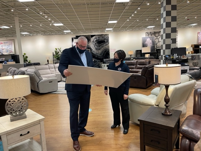 Todd Peter, Bob's Discount Furniture Regional Manager, reads a ceremonial check for $80,000 before he presents it to Darcy Clardy from Operation Homefront.
